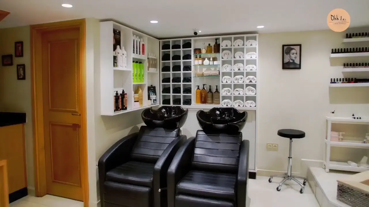 Espace de lavage, fauteuils noirs et étagères de serviettes du salon